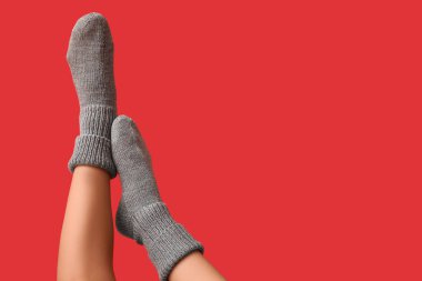 Kırmızı arka planda gri örgülü çoraplı genç kadın bacakları.
