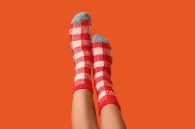 Turuncu arka planda sıcak kareli çoraplı genç kadın bacakları.