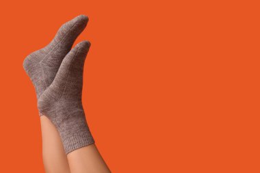 Turuncu arka planda gri pamuklu çoraplı genç kadın bacakları