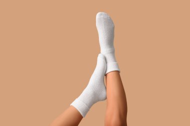 Kahverengi arka planda beyaz pamuklu çoraplı genç kadın bacakları.