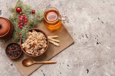 Bowl of traditional Ukrainian Kutya dish with Christmas tree branches and jug of uzvar on grey background clipart