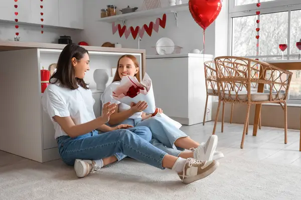 Genç lezbiyen kadın sevgilisini sevgililer gününde mutfakta güllerle selamlıyor.