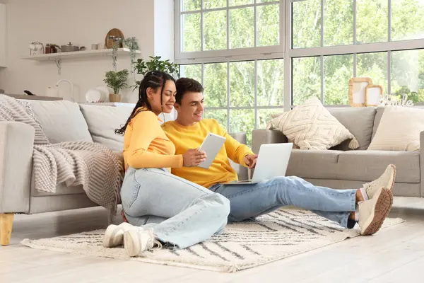 Evde dizüstü bilgisayar ve tablet bilgisayar kullanan genç bir çift