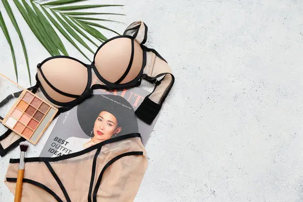 Şık kadın iç çamaşırları, göz farı, dergi ve arka planda palmiye yaprağı olan kompozisyon