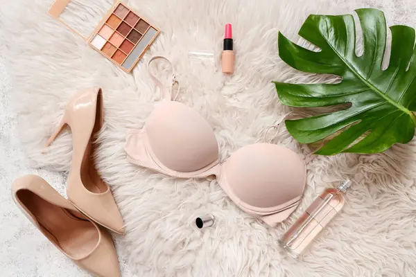 Kadın sütyeni, ayakkabı ve kozmetik ürünleriyle hafif kabarık halı üzerinde kompozisyon