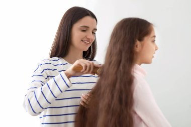 Genç anne banyoda küçük kızının saçını tarıyor.