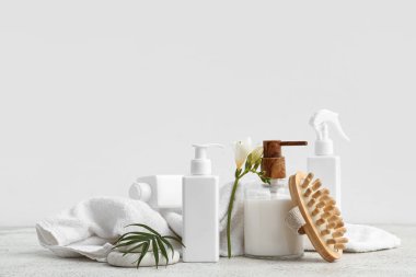 Kozmetik ürünler, masaj fırçası, temiz havlu ve çiçek.