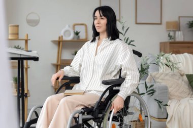 Evinin penceresinin yanında tekerlekli sandalyede güzel bir kadın.