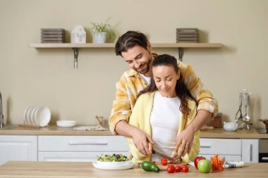 Evli çift mutfakta domates kesiyor.