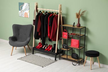 Modern giyinme odasının şık iç dekorasyonu, kadın kıyafetleri ve renkli duvarın yanındaki koltuk.