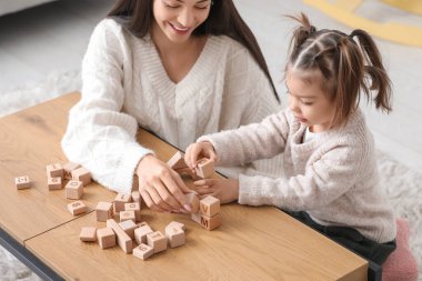 Öğretmen ve küpleri olan sevimli küçük kız masada alfabe öğreniyor.