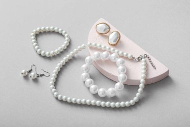 Gri arka planda güzel inci mücevherleri olan dekoratif podyum.