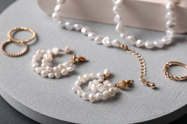 Gri arka planda farklı güzel mücevherlere sahip dekoratif podyumlar, yakın plan