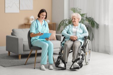 Genç hemşire ve tekerlekli sandalyedeki yaşlı kadın.