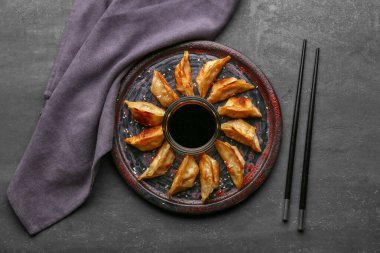Kızarmış Japon gyoza tabağı ve siyah arka planda soya sosu.