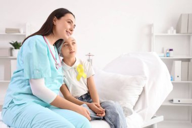 Kemoterapiden sonra sarı kurdeleli ve klinikte hemşirelik yapan küçük bir kız. Çocukluk kanseri farkındalığı