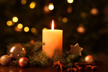 Noel ağacına karşı yanan mum, köknar dalları, süslemeler ve baharatlar içeren kompozisyon