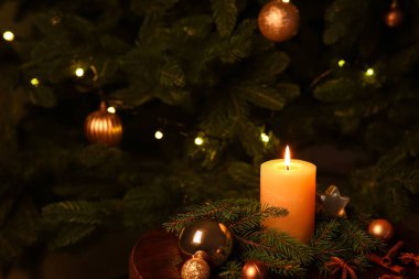 Yanan mum, köknar dalları ve kapalı bir Noel ağacı yakınındaki süslemelerle kompozisyon