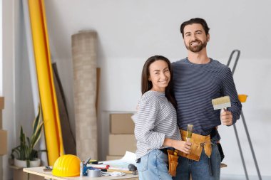 Boya fırçalı genç çift yeni evlerinde tamirat sırasında sarılıyorlar.