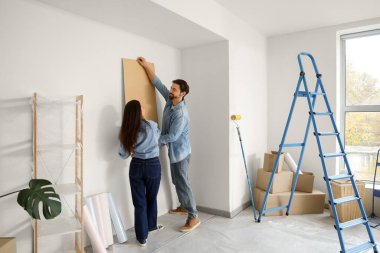 Beagle köpeği olan genç bir çift yeni evlerinde tadilat sırasında duvar kâğıdı yaptırıyor.