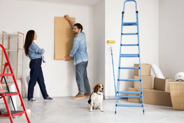 Beagle köpeği olan genç bir çift yeni evlerinde tadilat sırasında duvar kâğıdı yaptırıyor.