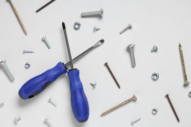 Gri arkaplanda tıklama cıvataları, vidalar ve tornavidalar