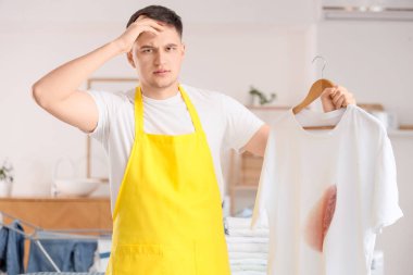 Evde yanmış tişörtü olan yakışıklı, hoşnutsuz bir genç.