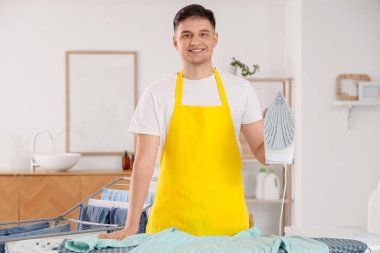 Evde demir ve gömleği olan yakışıklı genç adam.