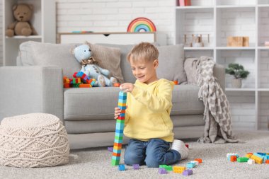 Evinde renkli oyuncak tuğlalarıyla kule inşa eden mutlu küçük çocuk.