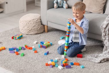 Evinde renkli oyuncak tuğlalarıyla kule inşa eden mutlu küçük çocuk.