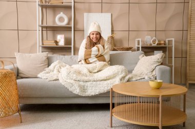 Kış günü evde sıcak ekoseli donmuş genç bir kadın.