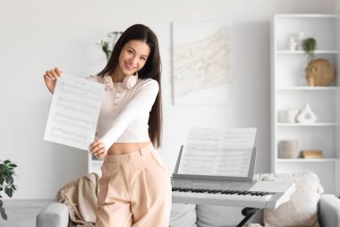 Evinde not defteri ve sentezleyicisi olan genç bir kadın.