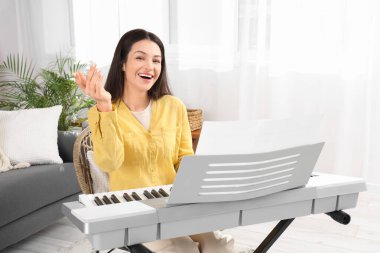 Mutlu genç kadın evde sentezleyici oynuyor.