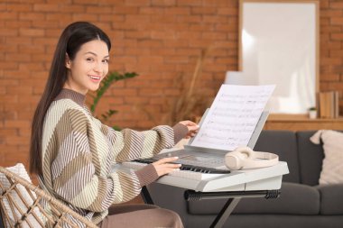 Not kâğıtlarıyla evde sentezleyici çalan güzel genç bir kadın.