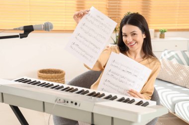 Evinde not kağıtları ve sentezleyicisi olan genç bir kadın.