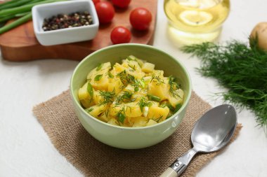 Bir kase lezzetli patates salatası, dereotlu, biberli ve domatesli beyaz arka plan