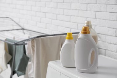 Çamaşır odasında çamaşır makinesinin üzerinde deterjan şişeleri, yakın plan.