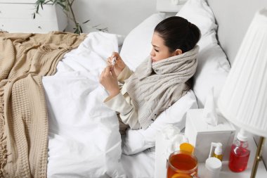 Yatak odasında termometresi olan hasta genç bir kadın.
