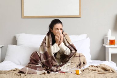 Yatak odasında hapşıran dokuları olan hasta bir genç kadın.