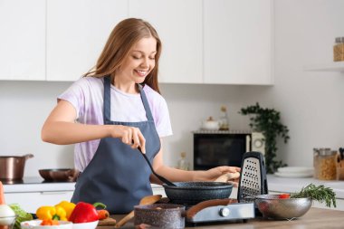 Mutfakta sebze kızartan genç bir kadın.