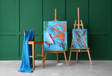 Resim sehpasında resimler ve resim atölyesinde kumaşlı sandalyeler.