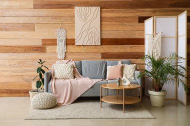 Oturma odasının iç tarafında pembe ekose ve kahve masalı bir kanepe.