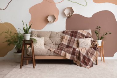 Oturma odasının içinde kareli ekoseli ve çiçekli rahat bir kanepe.