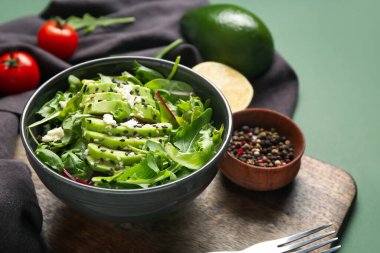 Lezzetli avokado salatası, mozzarella peyniri ve yeşil arka planda malzemeler.
