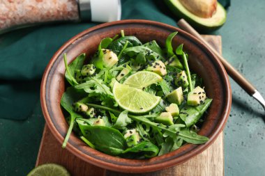 Yeşil arka planda limon ve susam tohumlu lezzetli avokado salatası, yakın plan.