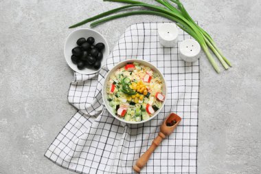 Bir kase salata ile yengeç çubuğu, mısır ve salatalık, gri grunge arka planda.