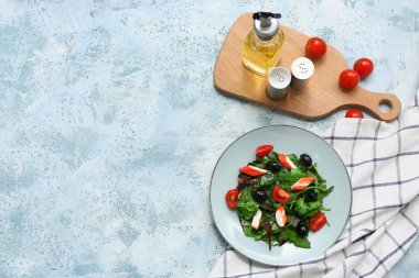 Yengeç çubuklu bir tabak salata, ıspanak, siyah zeytin ve domatesler mavi grunge arka planda.