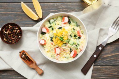 Bir kase salata ile yengeç sopası, mısır ve ahşap arka planda salatalık
