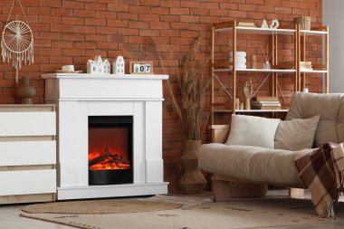 Şık modern oturma odasının içinde şöminesi, kanepesi ve tuğla duvarın yanındaki raf üniteleri var.