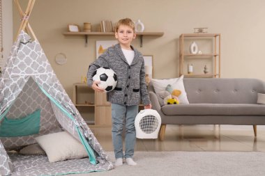 Evde elektrikli vantilatör ısıtıcısı olan şirin bir çocuk.